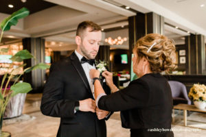 Groom's mother pins on boutineer in the lobby of the Axis Hotel